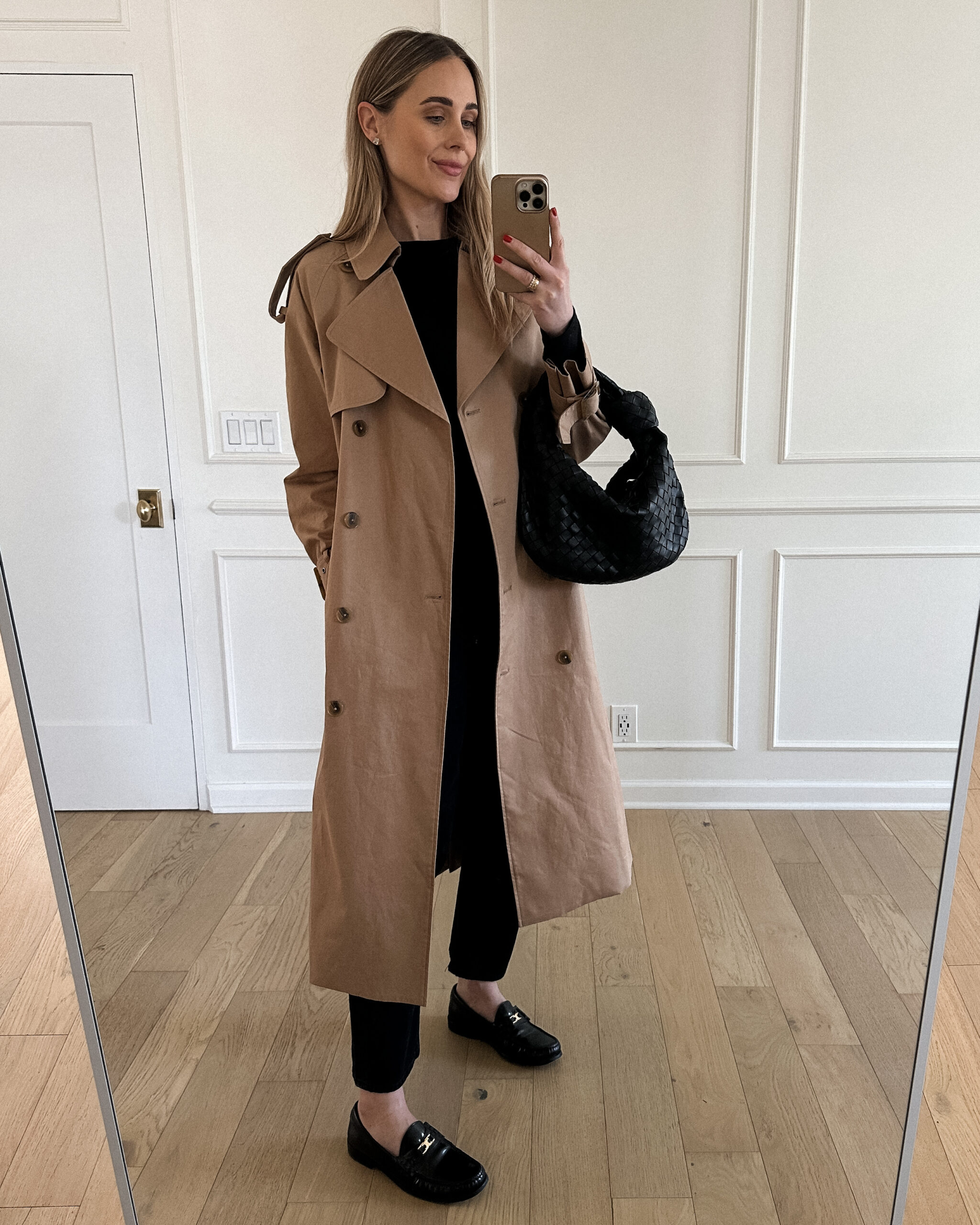 Fashion Jackson Wearing Mayson the label long trench coat, black long sleeve tee, agolde black jeans, celine black loafers, bottega veneta black teen jodie