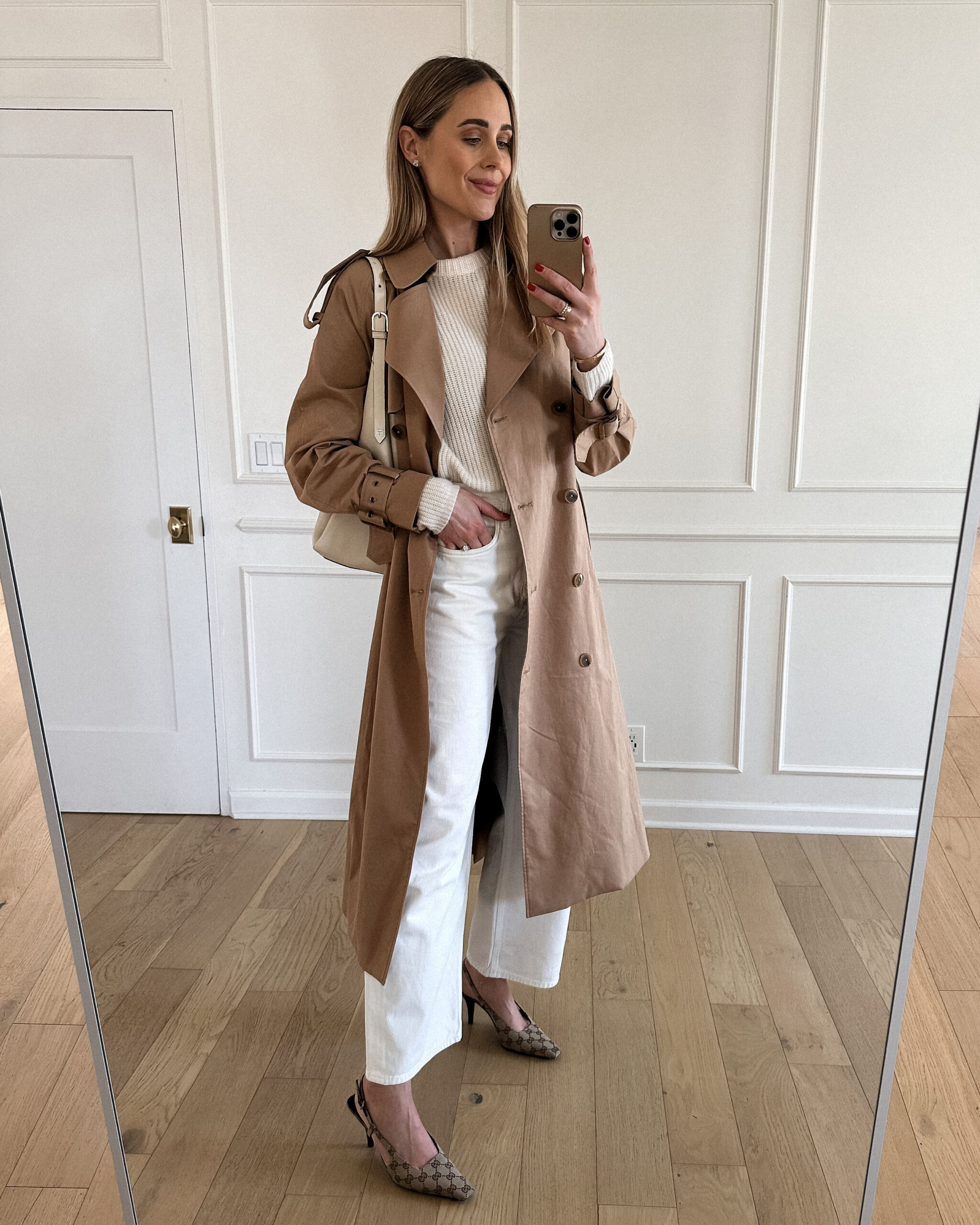 Fashion Jackson Wearing Mayson the label long trench coat, jenni kayne white fisherman cashmere sweater, white agolde jeans, gucci logo slingbacks, toteme white hobo bag