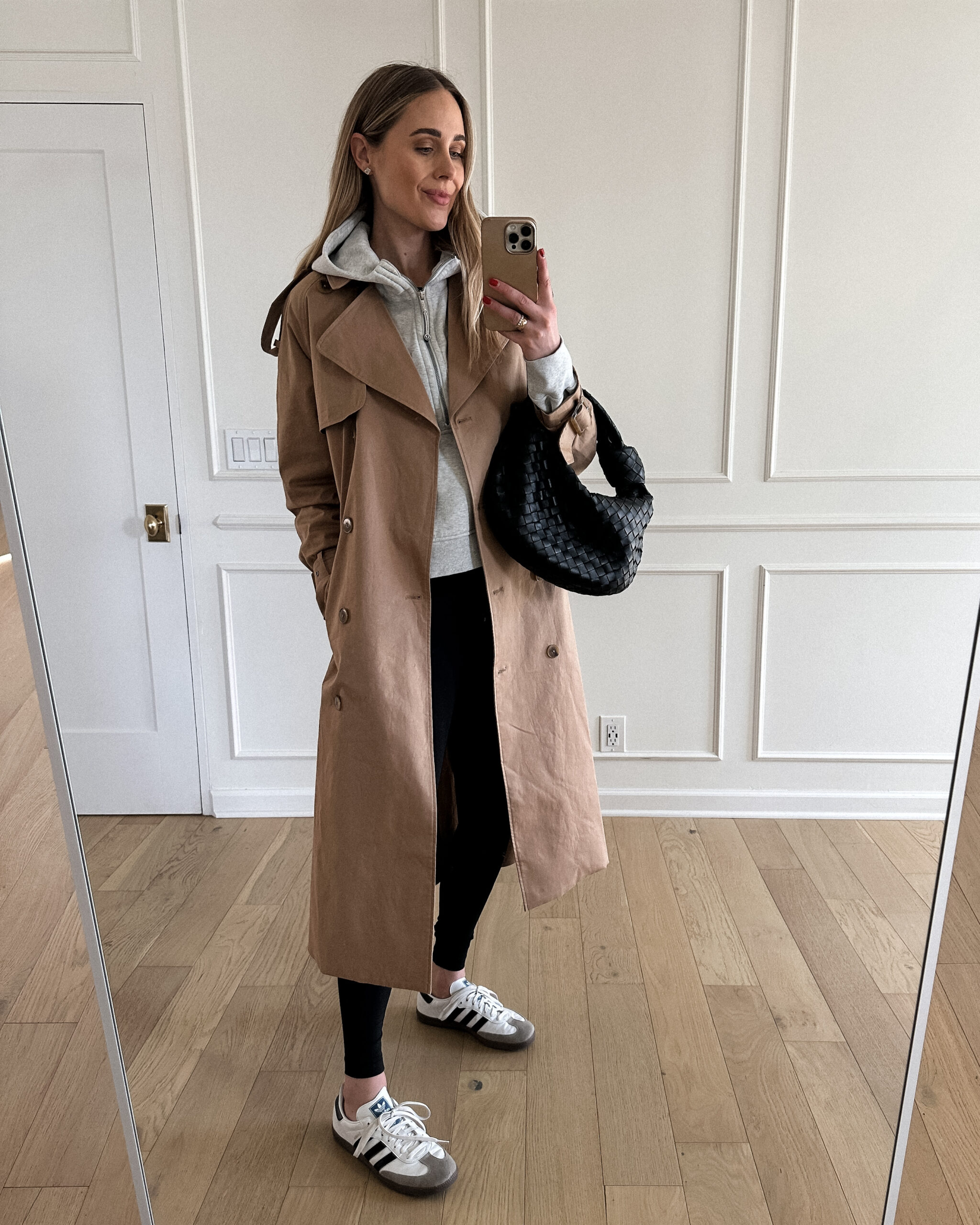 Fashion Jackson Wearing Mayson the label long trench coat, lululemon grey hoodie sweatshirt, lululemon black leggings, adidas samba sneakers, bottega veneta teen jodie black handbag