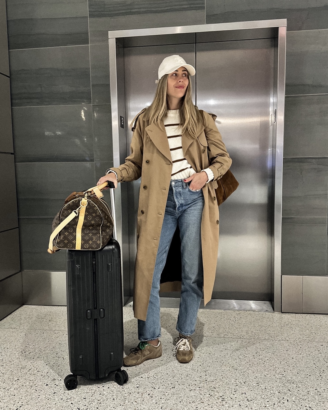 Fashion Jackson Travel Outfit Long Trench Coat White Celine Baseball Hat New Balance Miu Miu Sneakers Louis Vuitton Luggage